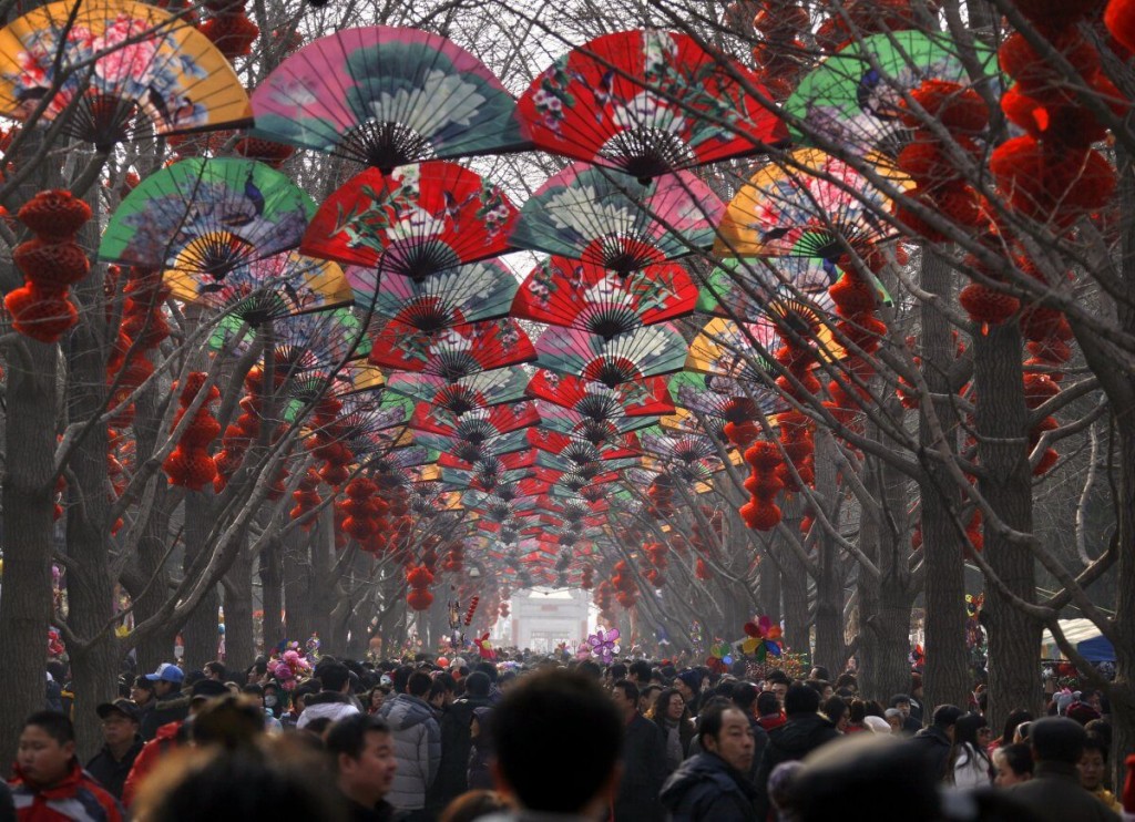 large-crowds-walk-under-a-row-of-trees-decorated-with-fans-and-red-lanterns-at-a-temple-fair-celebrating-the-chinese-new-year-in-beijing (1)