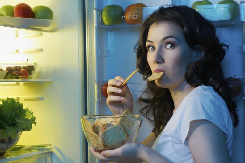 Девушка ест из холодильника