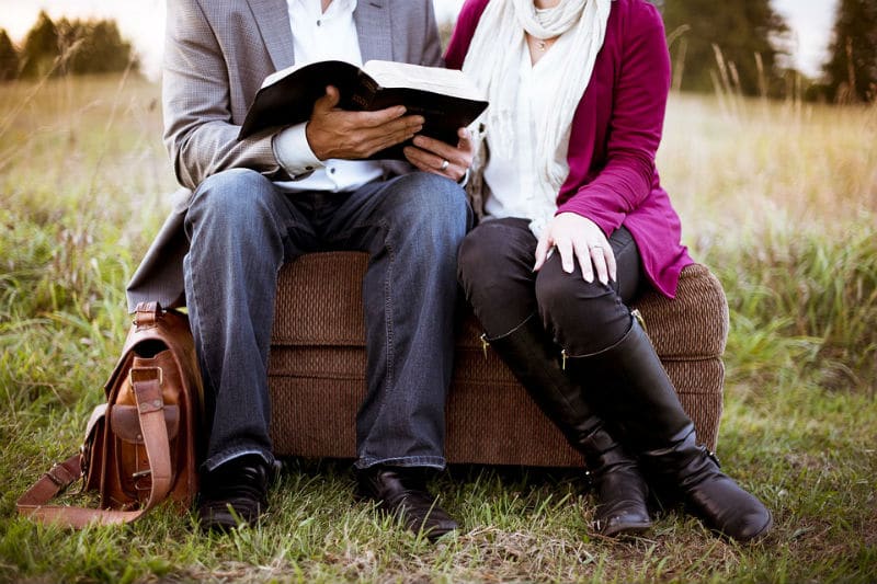 Влюбленная пара читает книгу на природе