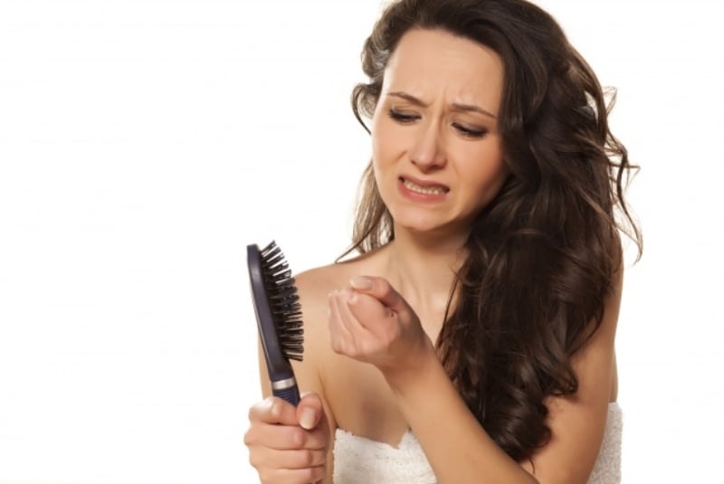 Девушка смотрит на расческу с выпадающими волосами