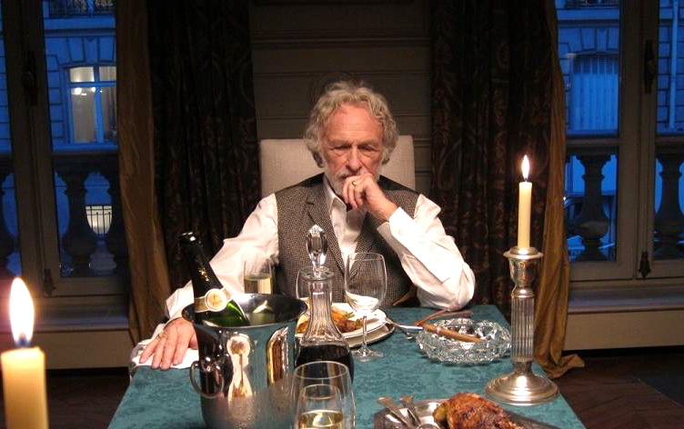 мужчина сидит за столом с едой и шампанским