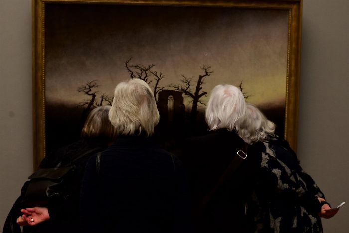четыре женщины седые смотрят на темную картину в музее