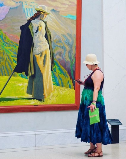 женщина смотрит на картину с девушкой в платье