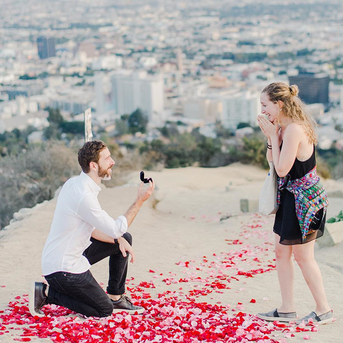 парень делает девушке предложение на горе над городом лепестки роз