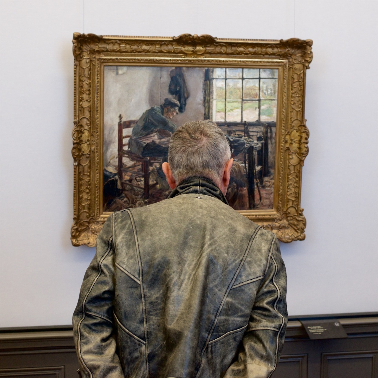 мужчина в кожаной куртке смотрит на мужчину в кожаной куртке на картине в музее