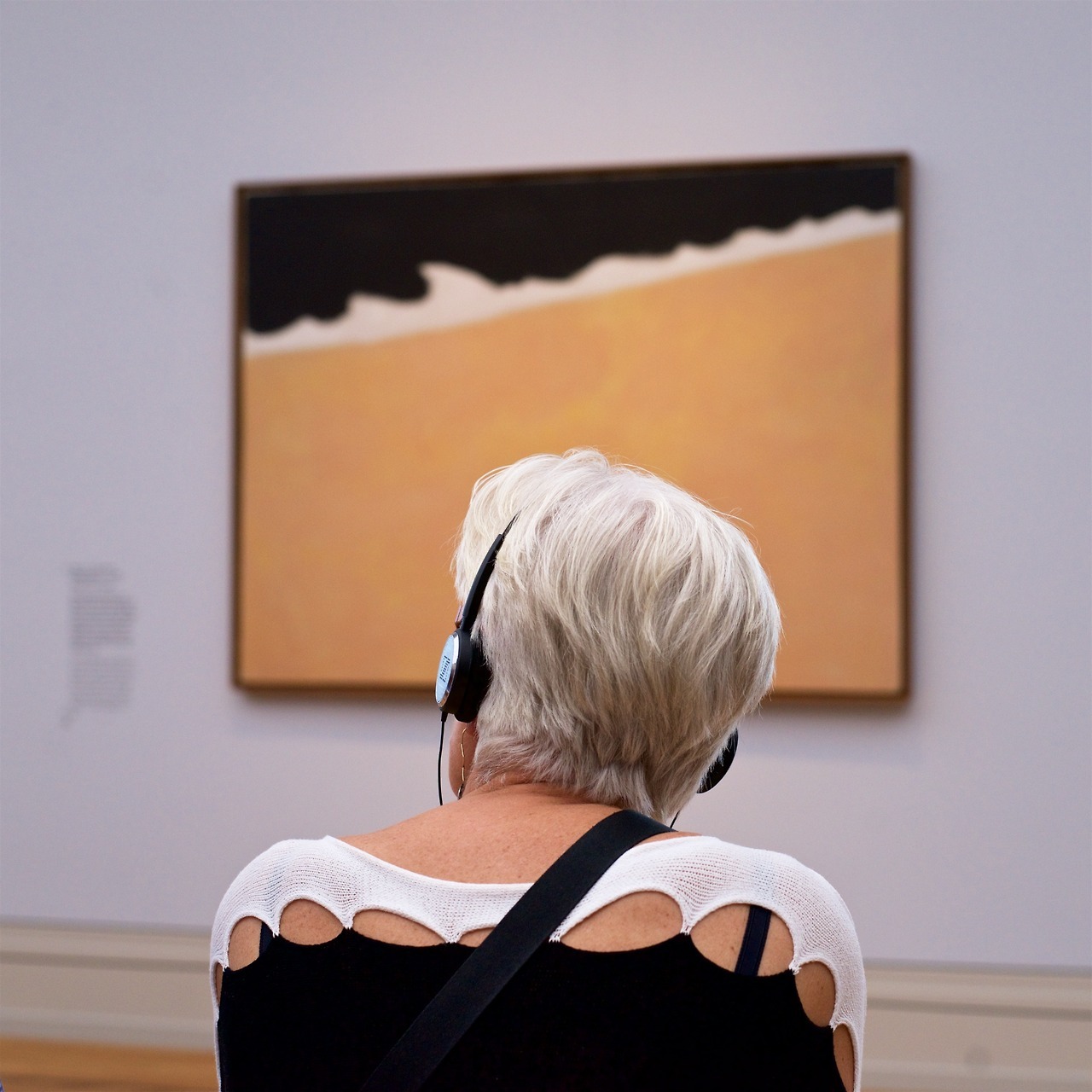 женщина в полосатом свитере смотрит на полосатую картину