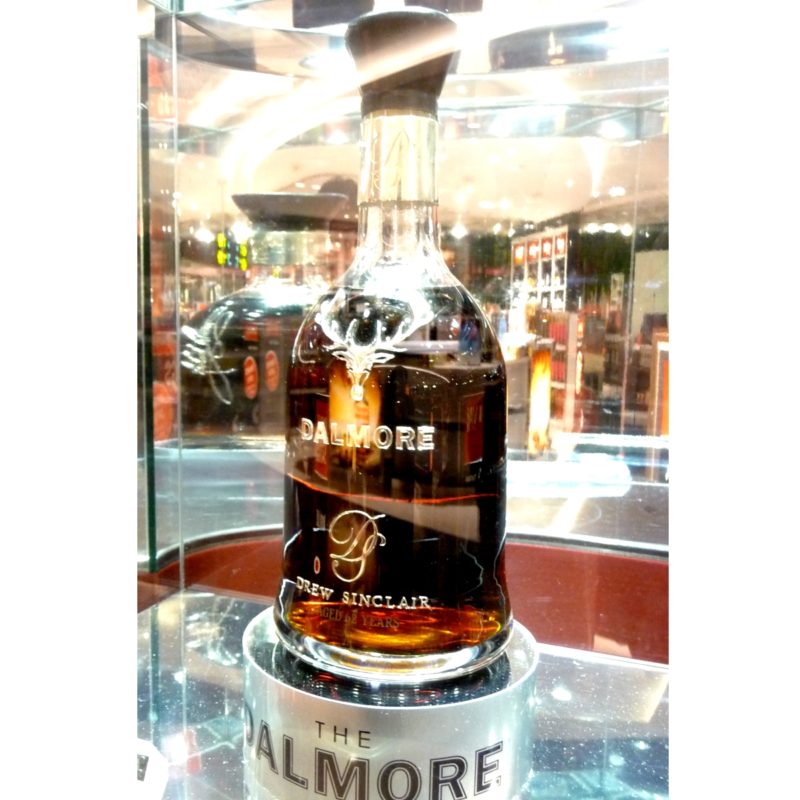 темно-янтарный виски Дэлмор 62 в светлой бутылке на витрине
