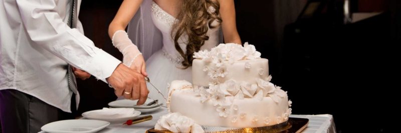 свадебный белый торт, который режут молодожены