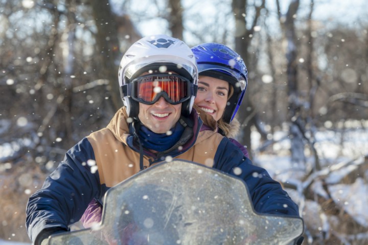 мужчина на зимнем скутере с девушкой по снегу