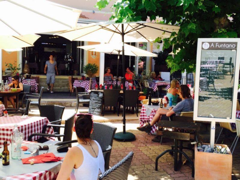 Ресторан A Funtana на Корсике - вид со стороны террасы на сидящих за столами людей. Справа - меню.