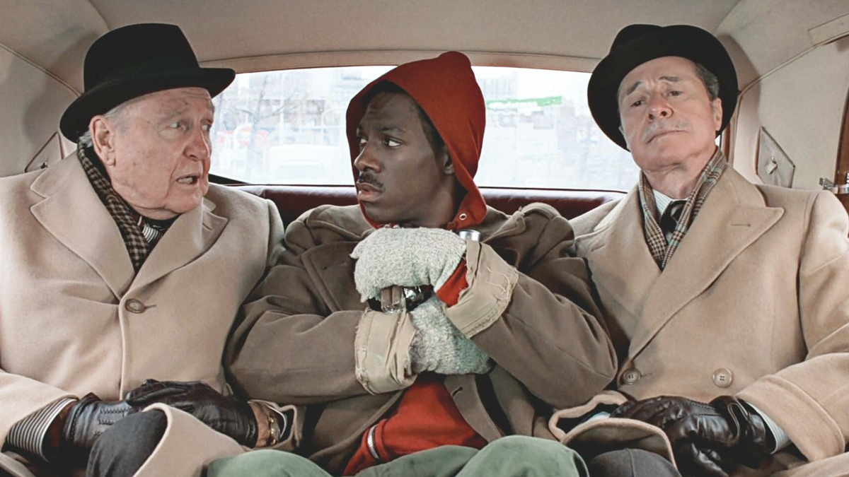 между двумя белыми джентльменами в машине сидит темнокожий веселый парень