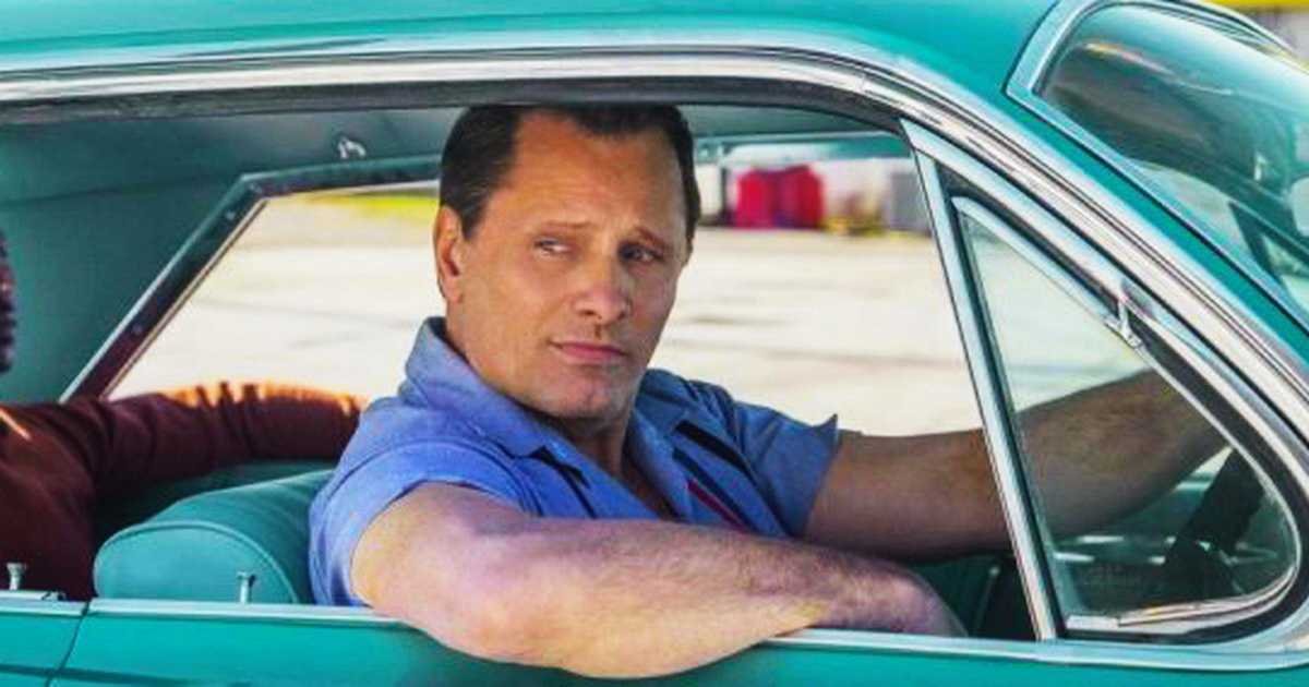 мужчина в голубой рубашке за рулем крутой бирюзовой ретро-машины