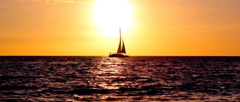 парусная яхта в море на фоне заходящего солнца