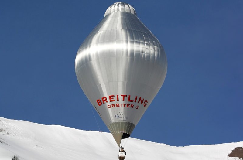 аэростат Фоссета Breitling Orbiter 3 в небе на фоне снежных вершин