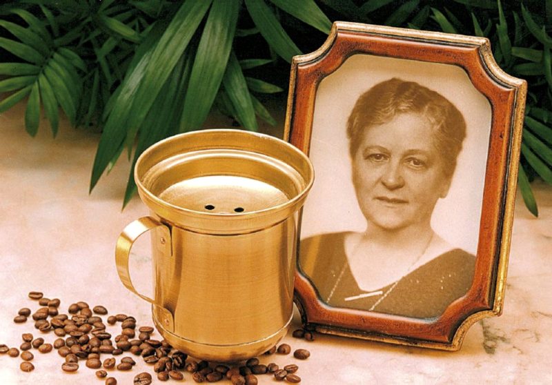 портрет Мелитты Бенц, чашка с кофейным фильтром и зерна кофе