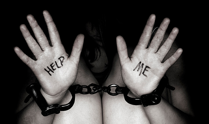 женщина в наручниках и с надписью "помогите" на руках