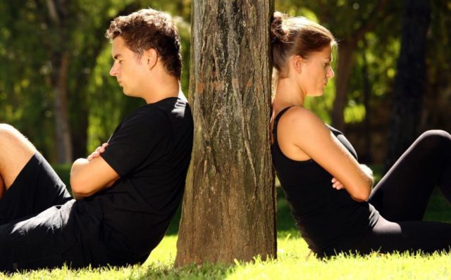парень и девушка сидят с двух сторон дерева
