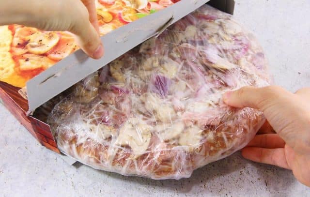 человек вытаскивает замороженную пиццу из упаковки