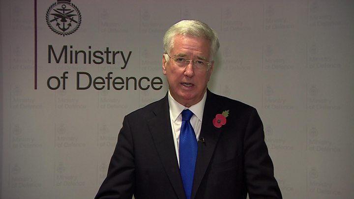 Мужчина на фоне символа Министерства Обороны Великобритании