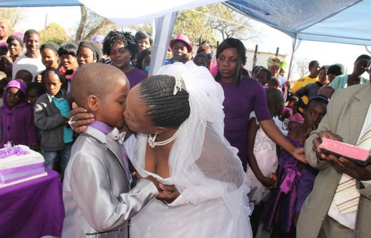 престарелая невеста целует маленького жениха