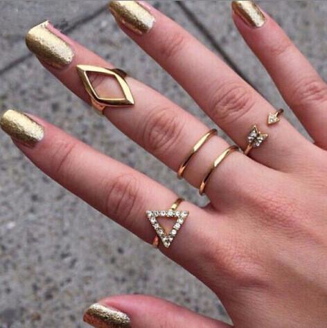 рука с золотистыми ногтями и золотыми кольцами