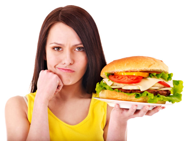 девушка держит гамбургер в руке