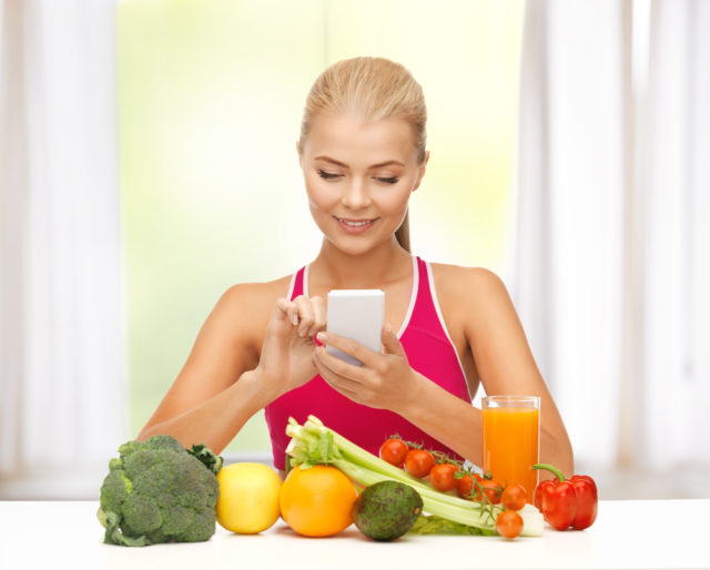 блондинка с телефоном и овощи на столе