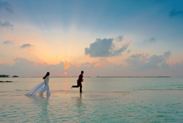 жених и невеста бегут по воде на закате