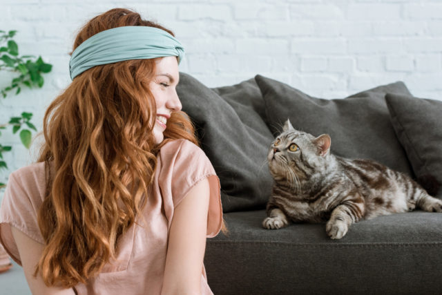 рыжеволосая девушка и полосатый кот на диване