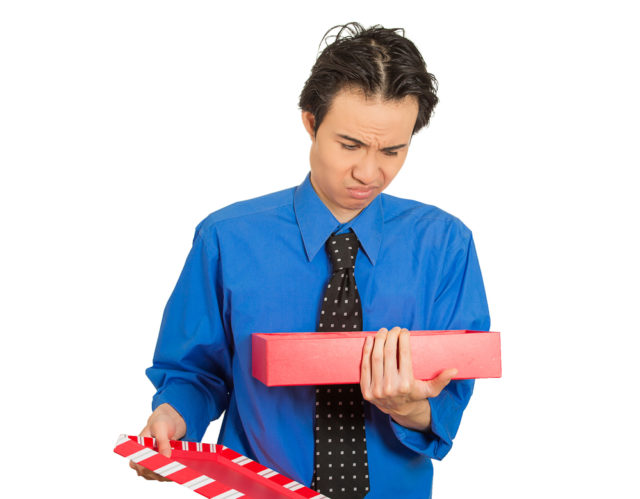 мужчина расстроенно смотрит на коробку с подарком