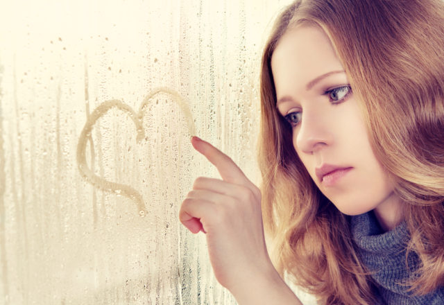 девушка рисует сердечко на запотевшем окне