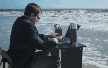 мужчина печатает на ноутбуке на берегу моря