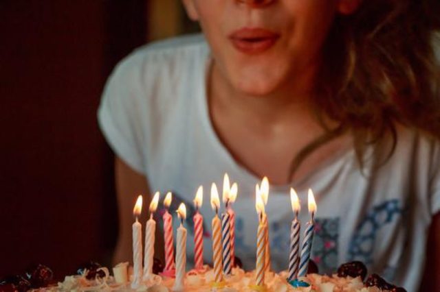 девушка задувает свечи на торте