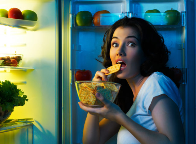 девушка ест печенье у холодильника