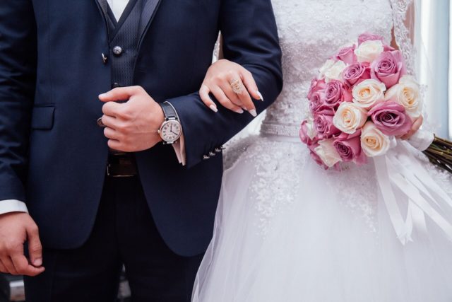 жених держит под руку невесту с букетом