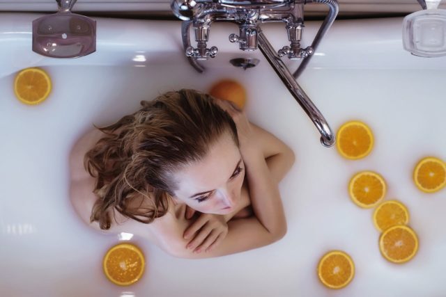 девушка принимает ванну с апельсинами