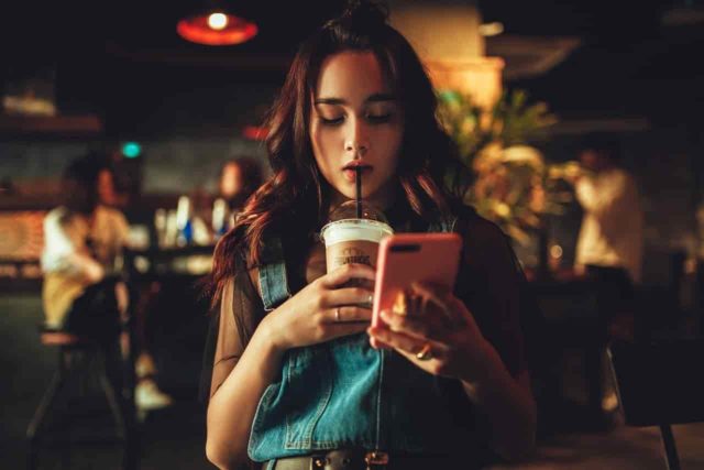 девушка с телефоном и кофе в кафе