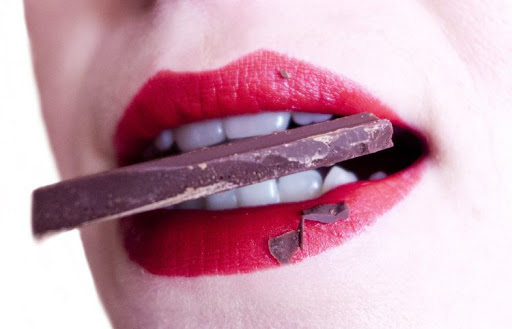 женщина с кусочком шоколада во рту