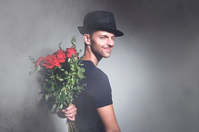 мужчина в шляпе с букетом роз за спиной