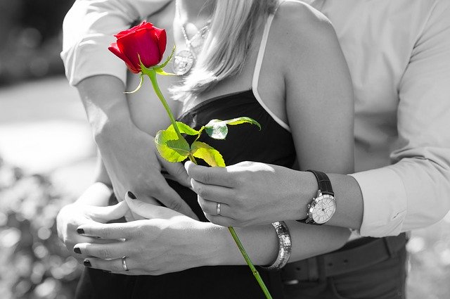 мужчина обнимает девушку с розой в руке