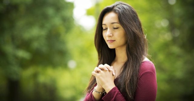 девушка молится с закрытыми глазами