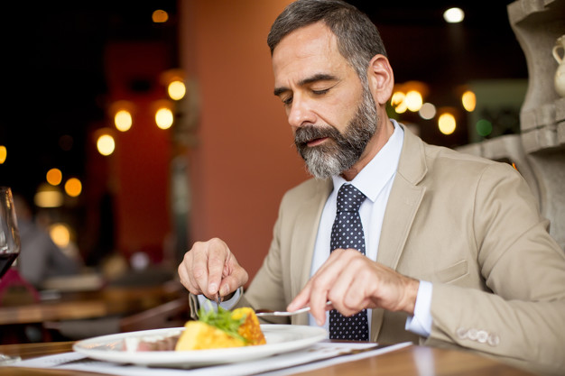 бородатый мужчина в костюме ест в ресторане
