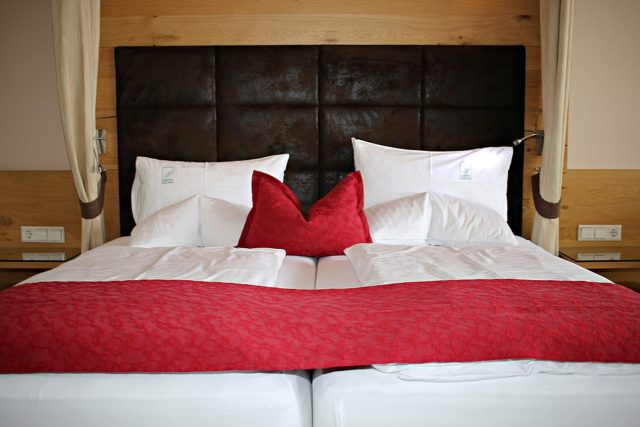 двуспальная кровать с белым постельным и красным покрывалом