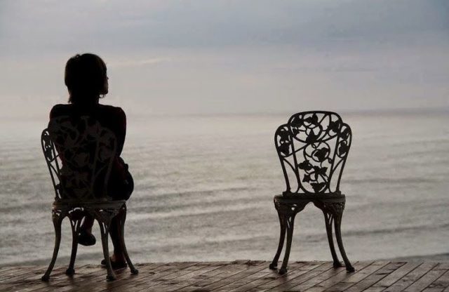 девушка сидит на стуле на берегу моря