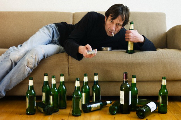 мужчина на диване с пивными бутылками на полу