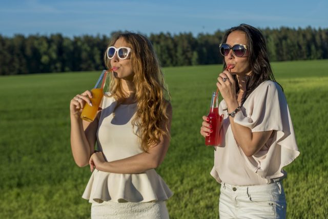 две девушки пьют безалкогольные напитки на природе