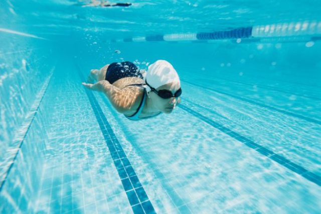 девушка плывет под водой в бассейне