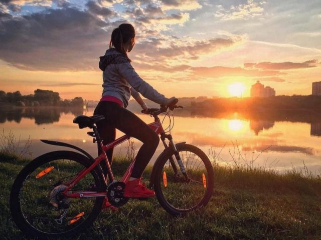 девушка на велосипеде смотрит на закат