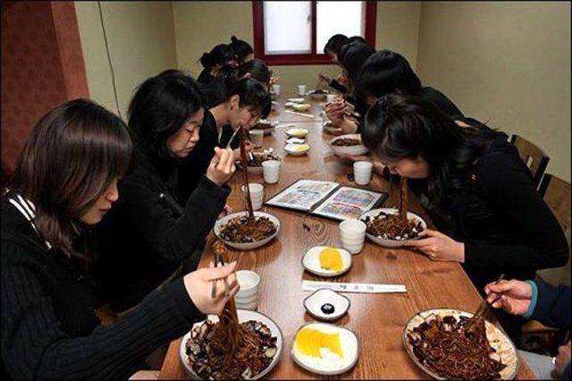 корейцы в черной одежде едят лапшу