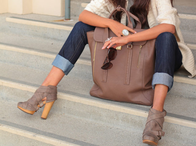 девушка сидит на ступеньках с большой коричневой сумкой